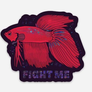 May include: A red betta fish sticker with the text "FIGHT ME". The fish has detailed fins and a dark purple border with small star-like accents. The sticker is a vibrant illustration.