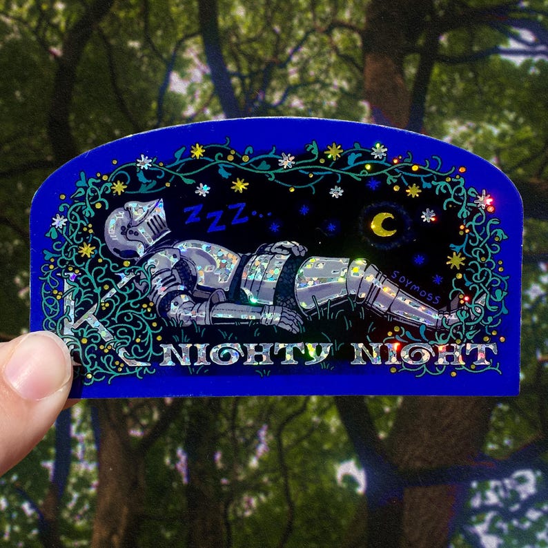 May include: A blue sticker with a sleeping knight in silver armor, surrounded by stars, a crescent moon, and floral accents. The text "NIGHTY NIGHT" is at the bottom. The sticker is held by a hand.
