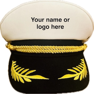 May include: White captain's hat with a black brim and gold braid trim. The hat has a black band with gold embroidered leaves on either side. The top of the hat has the text "Your name or logo here".