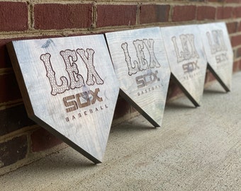 Op de afbeelding: Vier houten homeplate-borden met de tekst "LEX SOX BASEBALL" in een decoratief lettertype. De borden zijn in een rij geplaatst, met het eerste bord het dichtst bij de camera en het laatste bord het verst weg.