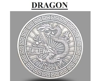 May include: A circular silver-toned metal coin featuring an embossed dragon design in the center, surrounded by a geometric border pattern. The coin includes the text DRAGON at the top, the Chinese characters 辰龍, and the word loong at the bottom.