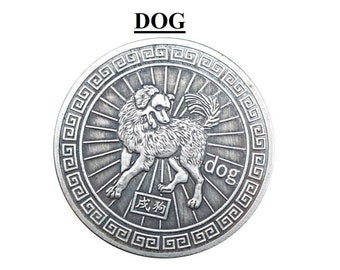 May include: A circular silver-toned metal coin featuring a relief of a dog in the center, surrounded by a geometric border. The word DOG is printed above the coin, while the word dog and Chinese characters are embossed on the coin surface.