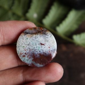 May include: A white ceramic mug with a black handle and the text "But First, Coffee" in a bold, black font. The mug is sitting on a wooden surface. The mug is approximately 4 inches tall.