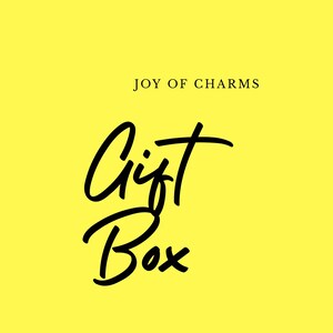 May include: A yellow background with black text that reads "JOY OF CHARMS" and "Gift Box" in a handwritten style.