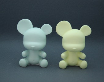 May include: Two small, unpainted, ceramic teddy bear figurines. One is light blue and the other is light yellow.