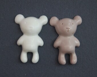 May include: Two ceramic teddy bear figurines. One is white and the other is a light brown color.