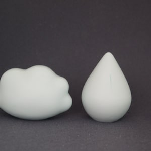 May include: Two ceramic sculptures, one shaped like a cloud and the other shaped like a raindrop. Both sculptures are a light blue color.