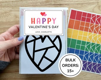 May include: A clear plastic sleeve containing a card with a black geometric heart outline and a label that reads HAPPY VALENTINE'S DAY LOVE, CHARLOTTE. Next to it is a sheet of rainbow-colored square stickers and a circular label reading BULK ORDERS: 15+.