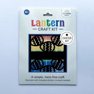 May include: A white craft kit package with the text "Lantern CRAFT KIT" in colorful letters. The kit includes black cut-out Easter egg shapes. The package also says "A simple, mess free craft" and "Decorate with included stickers, no paint needed!"