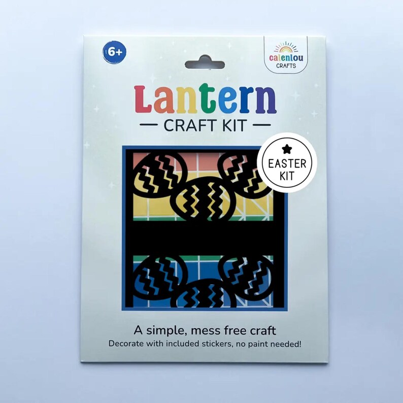 May include: A white craft kit package with the text "Lantern CRAFT KIT" in colorful letters. The kit includes black cut-out Easter egg shapes. The package also says "A simple, mess free craft" and "Decorate with included stickers, no paint needed!"