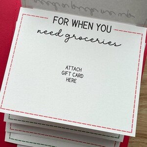 Pu&ograve; includere: Una pila di biglietti bianchi con bordi a puntini rossi e la scritta "FOR WHEN YOU need groceries." Le carte dicono anche "ATTACH GIFT CARD HERE." Le carte sono su uno sfondo rosso.