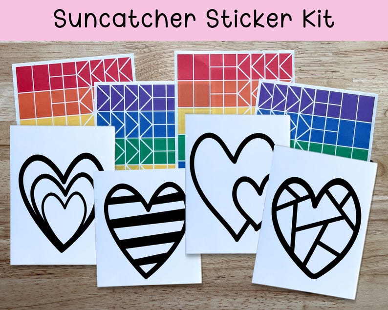 May include: A Suncatcher Sticker Kit featuring various designs. The kit includes stickers with geometric rainbow patterns and black heart designs. The text "Suncatcher Sticker Kit" is at the top of the image. The stickers are on a wooden surface.