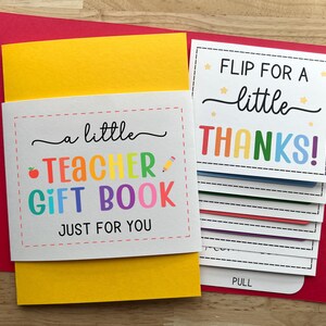 May include: A teacher gift book with a yellow cover and a red envelope. The book has the text "a little TEACHER GIFT BOOK JUST FOR YOU" and "FLIP FOR A little THANKS!" in colorful letters. The book has pull-out cards.