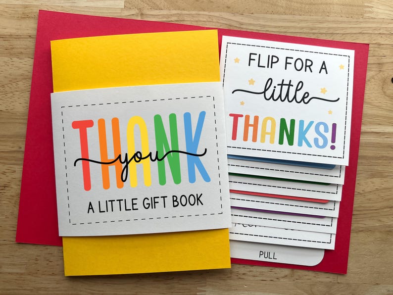 May include: A colorful "Thank You" gift book with a red envelope. The book has a yellow cover and features the text "Thank You" in rainbow colors. The inside pages say "Flip for a little Thanks!"