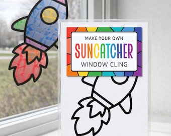 May include: A DIY rocket ship suncatcher window cling kit in a clear plastic sleeve. The kit features a black and white outline of a rocket ship and a label that reads MAKE YOUR OWN SUNCATCHER WINDOW CLING. A finished rocket suncatcher is visible.