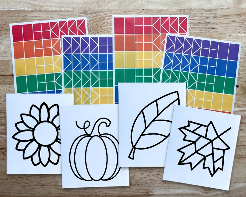 Op de afbeelding: Een set knutselbenodigdheden bestaande uit vier rechthoekige vellen met regenboogkleurige geometrische rasterpatronen en vier witte vierkante kaarten met zwarte lijntekeningen van een zonnebloem, een pompoen, een blad en een esdoornblad.