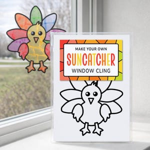 May include: A Make Your Own Suncatcher Window Cling kit featuring a black and white turkey outline on a white card. A finished, colorful turkey suncatcher with multi-colored feathers is displayed on the window glass behind the kit.