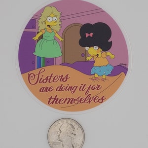 May include: A round sticker featuring a cartoon image of two women from The Simpsons. The sticker has the text "Sisters are doing it for themselves". The women are in a room with a door and a rainbow. A quarter is at the bottom.