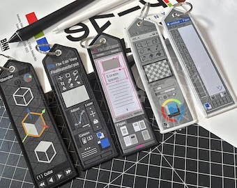 May include: Five black and white embroidered keychains featuring software interface designs. The keychains include designs for Blender, Photoshop, and other digital art programs. Each keychain has a silver ring for attachment.