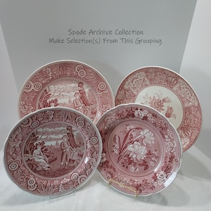 May include: Four ceramic plates from the Spode Archive Collection featuring pink and white transferware patterns. Two plates display pastoral scenes with figures, while the other two feature detailed floral arrangements with intricate borders.