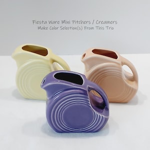 May include: Three Fiesta Ware mini pitchers or creamers in yellow, purple, and peach. Each ceramic piece features a circular ringed design and a handle. The text above reads: Fiesta Ware Mini Pitchers / Creamers Make Color Selection(s) From This Trio.