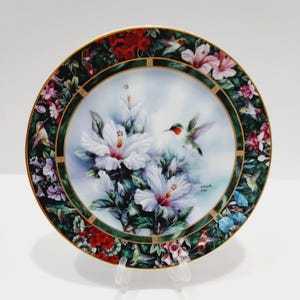 May include: A white ceramic mug with a black handle and the text "But First, Coffee" in a handwritten style. The mug is on a white surface. The mug is approximately 4 inches tall.