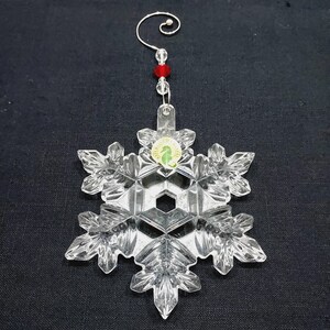 Stunning ornament with decorative hanger is in excellent condition and in original box which shows minimal wear. Clear crystal with hand-cut texturing on a snowflake design. It measures approximately 4-1/2" x 4" x 1/2", and with the hanger in place, the ornament extends to about 7-1/2" long. Made in Slovenia. Waterford 2014 Annual Christmas Ornament
