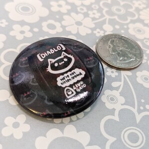 May include: Black and white button with a black cat illustration and the text "[DIABLO] We're not kitten around LIVE GATO".