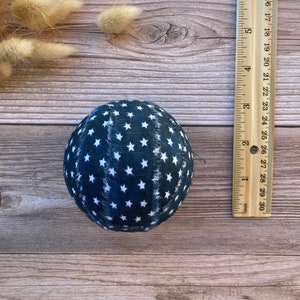 Puede incluir: Una bola de tela azul con estrellas blancas. La bola tiene un di&aacute;metro de aproximadamente 7,5 cm.