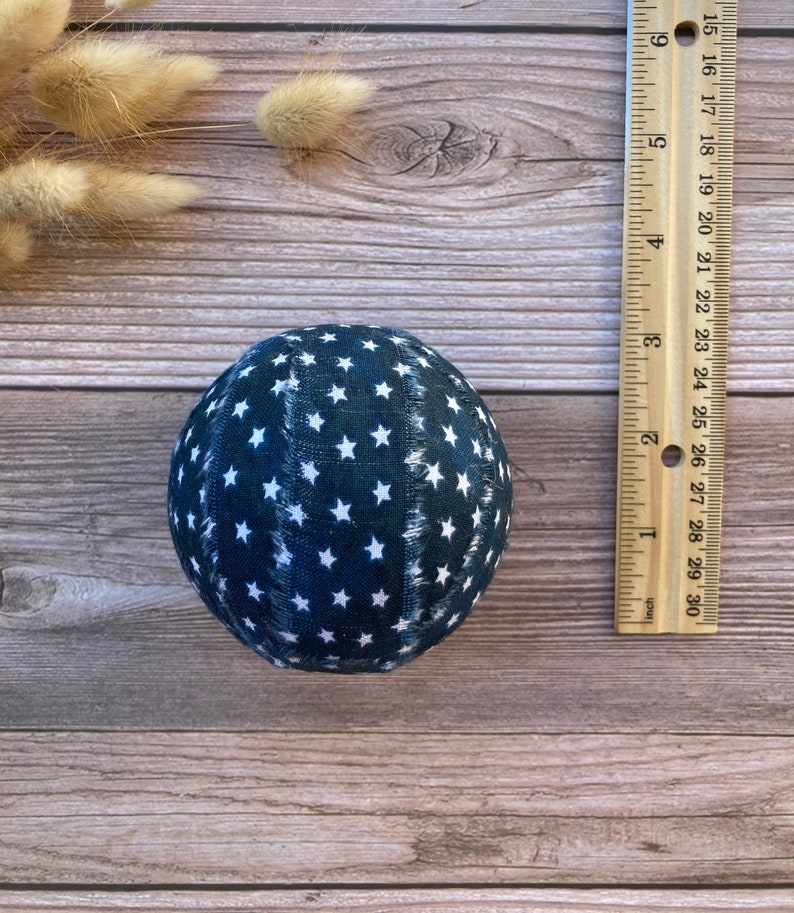 Puede incluir: Una bola de tela azul con estrellas blancas. La bola tiene un di&aacute;metro de aproximadamente 7,5 cm.