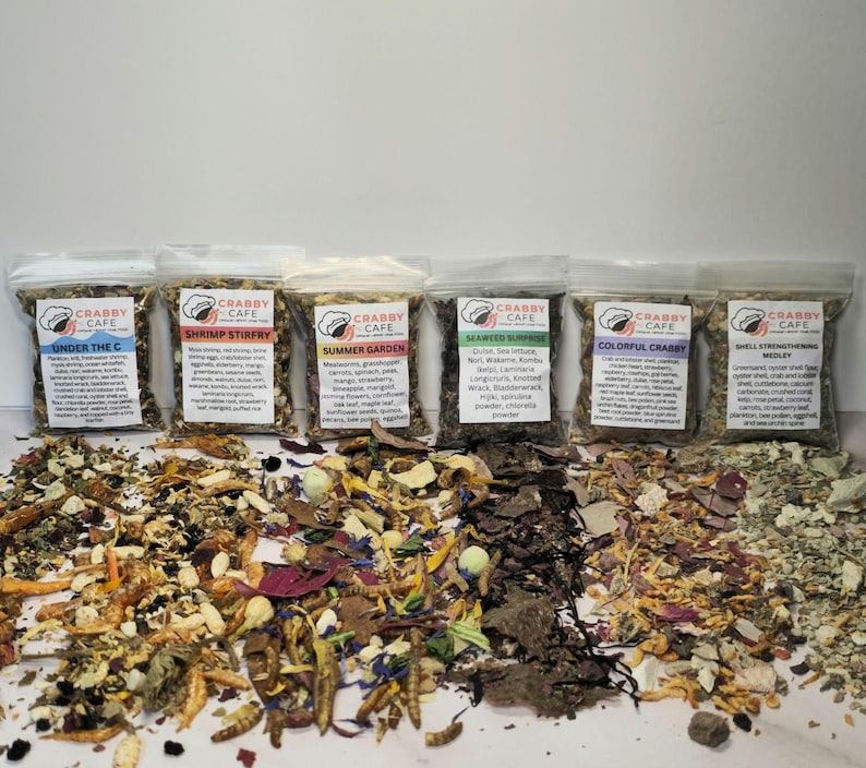 May include: Six clear bags of Crabby Cafe crab food mixes, each with a different label. The mixes include "Under the C", "Shrimp Stirfry", "Summer Garden", "Seaweed Surprise", "Colorful Crabby", and "Shell Strengthening Medley". The ingredients are visible.