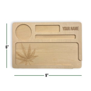 May include: A wooden rolling tray with a leaf design, a small circle, and a rectangular space for storing items. The tray is 23 cm long and 15 cm wide. The tray has a space for a name, which says "YOUR NAME".