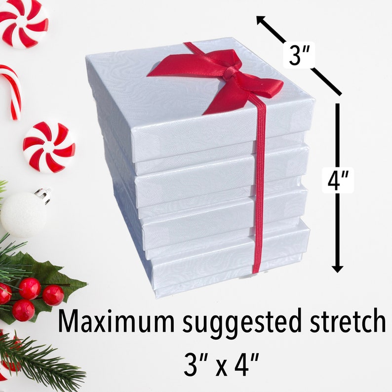 Puede incluir: Pila de cinco cajas de regalo blancas con una cinta roja atada alrededor. Las cajas miden 7,6 cm de ancho y 10,2 cm de alto. Estiramiento m&aacute;ximo sugerido 7,6 cm x 10,2 cm
