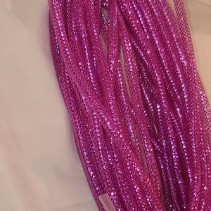 May include: A spool of pink metallic mesh ribbon. The ribbon is shiny and has a sparkly finish.