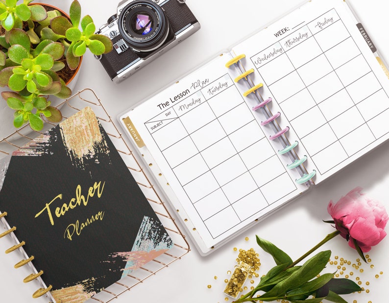 May include: A black and gold teacher planner with the text "Teacher Planner" on the cover. The planner is open to a weekly lesson plan page with the days of the week listed across the top. The planner is surrounded by a succulent plant, a camera, a rose, and gold beads.