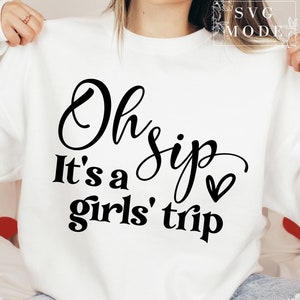 K&ouml;nnte beinhalten: Wei&szlig;er Pullover mit schwarzem Text, der "Oh sip it's a girls' trip" mit einem kleinen Herzen lautet.