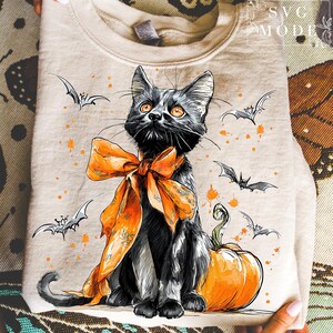 May include: Beige sweatshirt with a black cat wearing an orange bow, with bats and orange paint splatters. An orange pumpkin sits beside the cat. The sweatshirt has the text "SVG MODE" in the upper right corner.