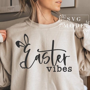 May include: A beige sweatshirt with the text "Easter vibes" and a bunny ear design.