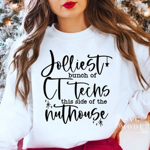 Puede incluir: Sudadera blanca con texto negro que dice "Jolliest bunch of CT Techs this side of the nuthouse" con una estrella y copos de nieve.