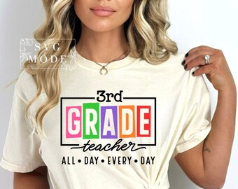 May include: A white t-shirt with the text "3rd GRADE teacher ALL DAY EVERY DAY" in black. The word "GRADE" is in colorful boxes.