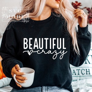 Pode incluir: Camisola de moletom preta com texto branco que diz "BEAUTIFUL crazy" com um s&iacute;mbolo de cora&ccedil;&atilde;o entre as palavras.