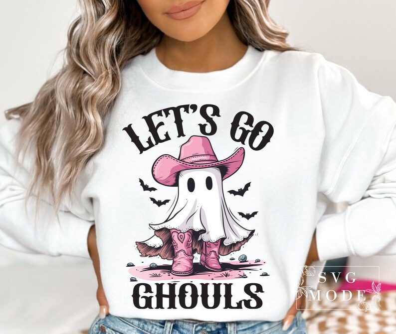 Może przedstawiać: Biała bluza z nadrukiem r&oacute;żowego ducha w r&oacute;żowym kowbojskim kapeluszu i butach. Na bluzce widnieje napis "Let's go ghouls".