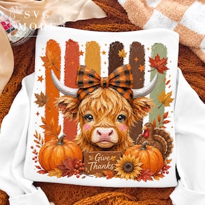 May include: A white sweatshirt featuring a graphic of a fluffy highland cow wearing a plaid bow, flanked by two orange pumpkins, a turkey, and autumn leaves. The design includes vertical textured stripes and a sign that reads Give Thanks.
