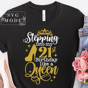 Pode incluir: Camiseta preta com um salto alto dourado e o texto "Stepping into my 21st Birthday like a Queen". O design inclui uma coroa e estrelas. A camisa &eacute; combinada com jeans azuis e rosas cor-de-rosa.