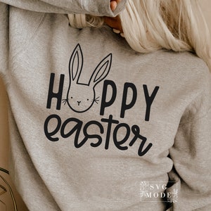 May include: A gray sweatshirt with the text "Hoppy Easter" in black lettering. A black and white cartoon bunny face is above the text.