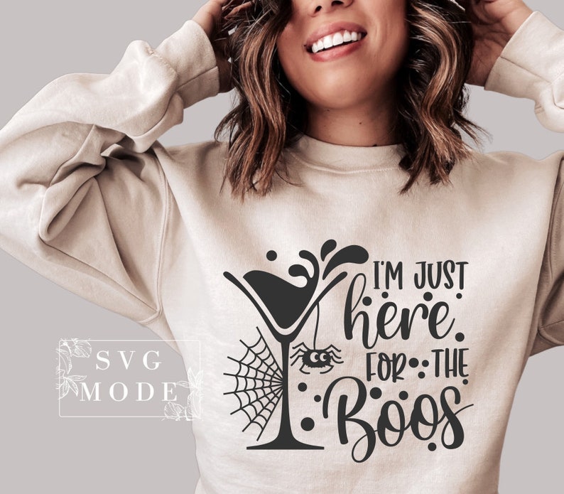 May include: A white sweatshirt with a black graphic design that says "I'm just here for the boos" with a martini glass and a spider web.