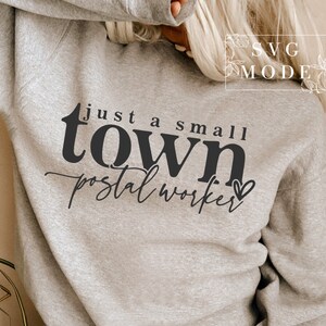 May include: Gray sweatshirt with the text "just a small town postal worker" in black lettering with a small heart.