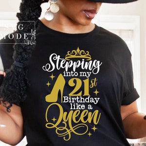 Pode incluir: Camiseta preta com um gr&aacute;fico dourado e branco. O gr&aacute;fico diz "Stepping into my 21st Birthday like a Queen" com um design de salto alto e coroa. A camisa tem gola redonda e mangas curtas.