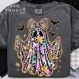May include: Dark gray sweatshirt featuring a colorful ghost design with a leopard print bow and trim. The ghost has black eyes and is surrounded by bats and stars. The text "SVG MODE" is in the upper left corner.