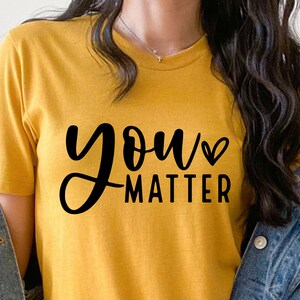 May include: A yellow t-shirt with the text "you matter" in black script with a small heart symbol after the word "you".